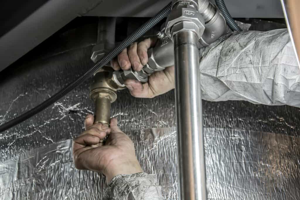 Plumber repairing pipes under sink — professional plumber website design